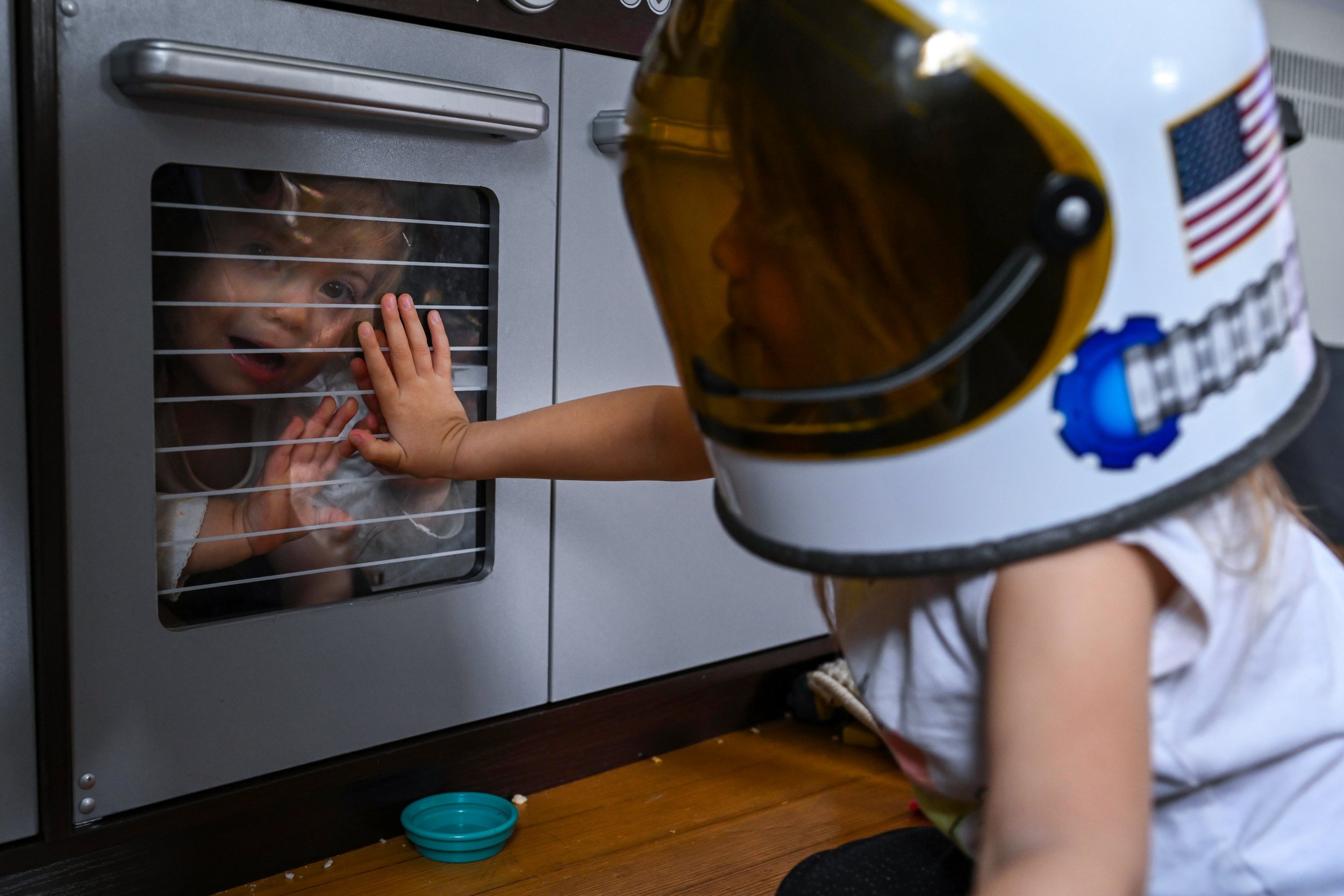 documentary family photographer girl trapping her sister inside play kitchen set