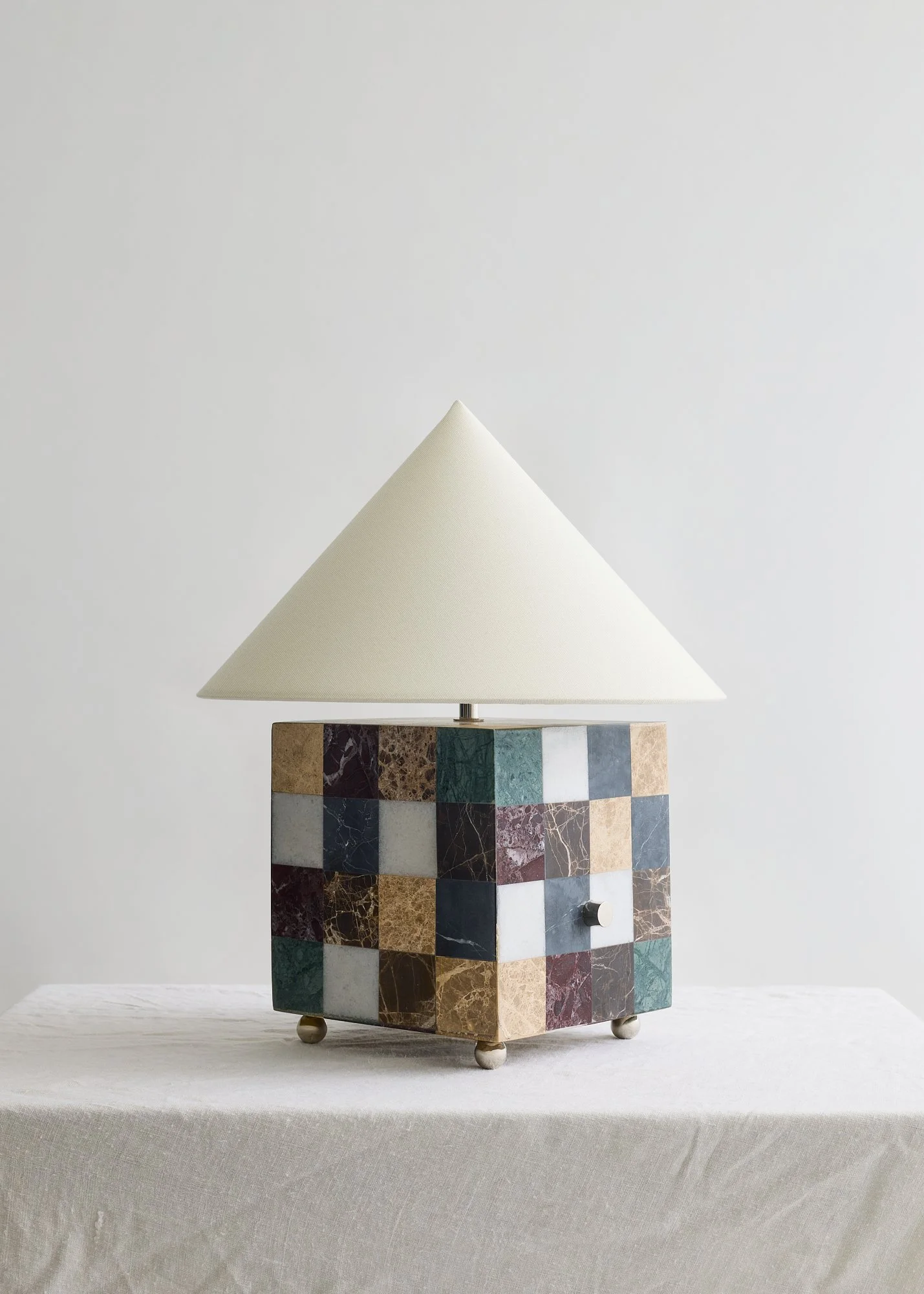 The Crews specimen marble table lamp with a pointed ivory fabric shade, shown against a light gray background.