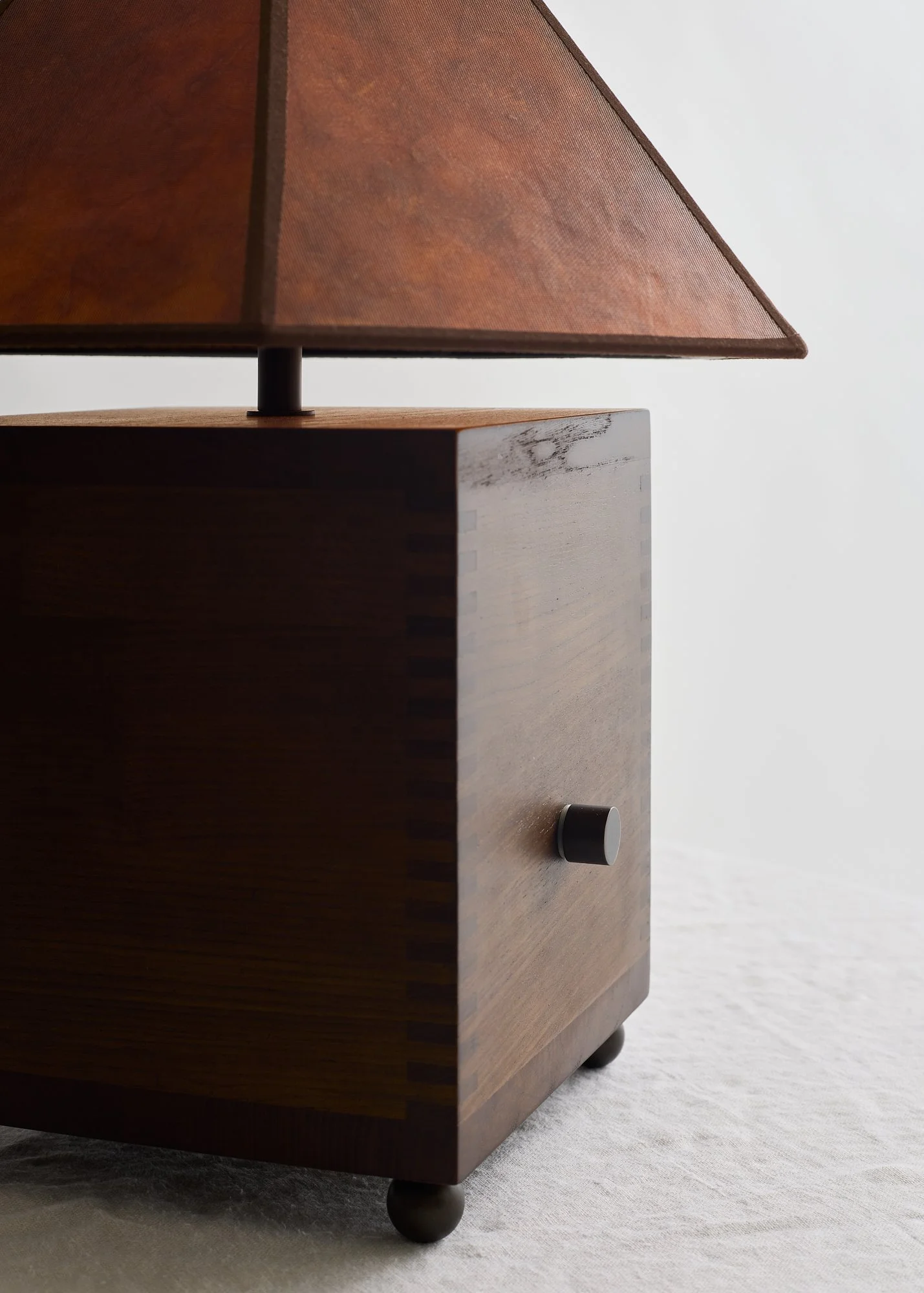 Close-up of The Carley lamp’s walnut grain, rotary dimmer knob, and amber mica shade.