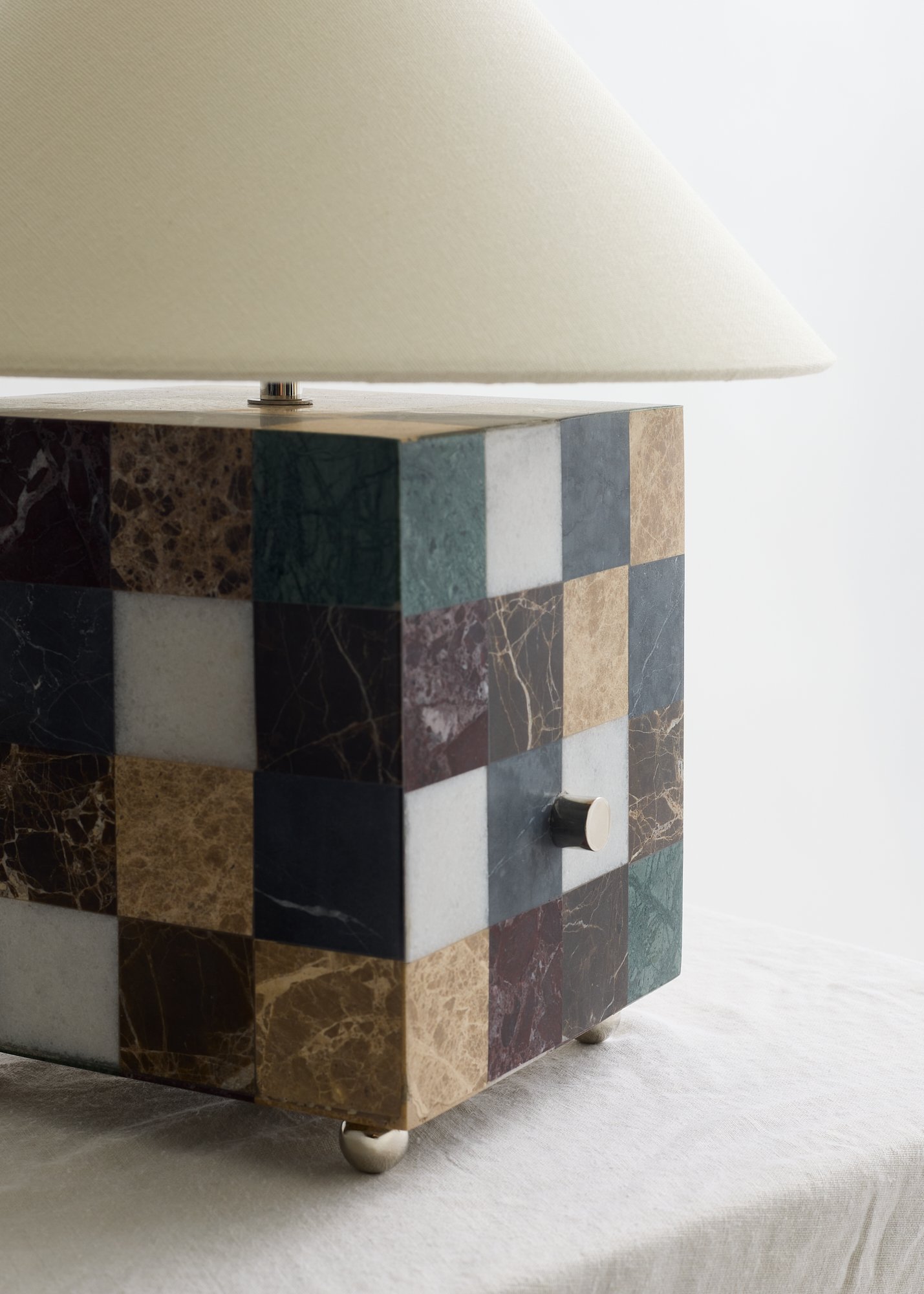 Close-up of The Crews lamp’s veined marble squares, rotary dimmer knob, and polished nickel ball feet.
