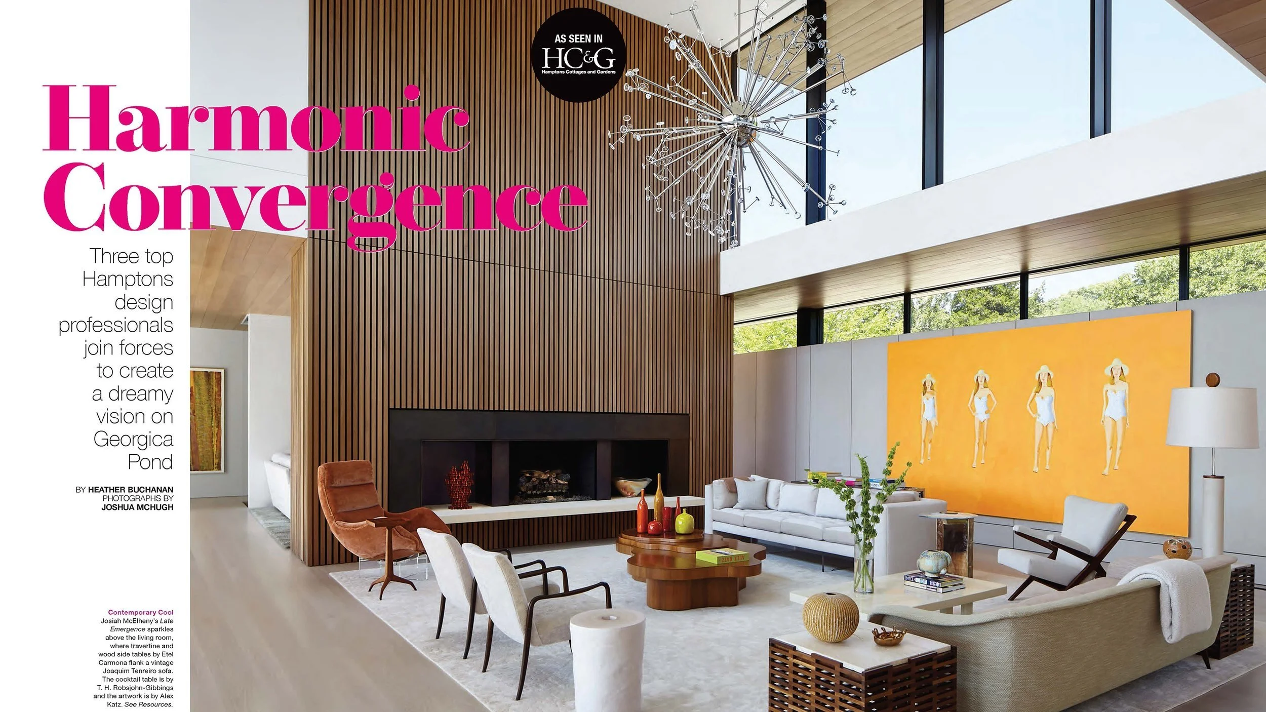 Interior of a modern living room with a high ceiling, large windows, and contemporary furniture, including a white sofa, a brown armchair, and a coffee table with decorative vases. Bright yellow artwork of four women in swimsuits hangs on the wall.