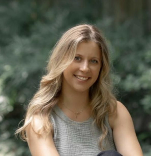 Smiling woman with long blonde hair outdoors.