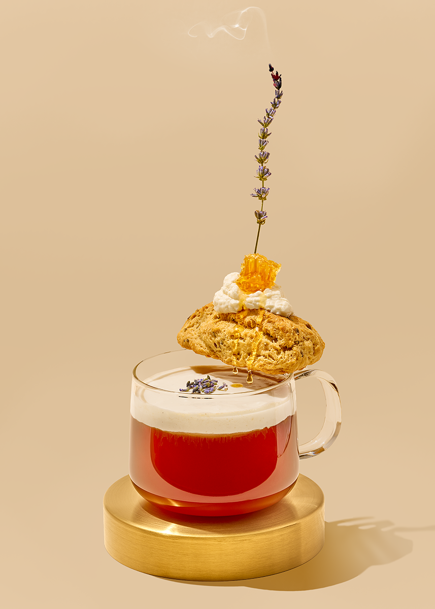 Commercial beverage photography by Suzanne Clements featuring an over-the-top London Fog tea with a vanilla whipped milk, lavender scone, clotted cream, hunk of honey comb, and a smoking sprig of lavender.