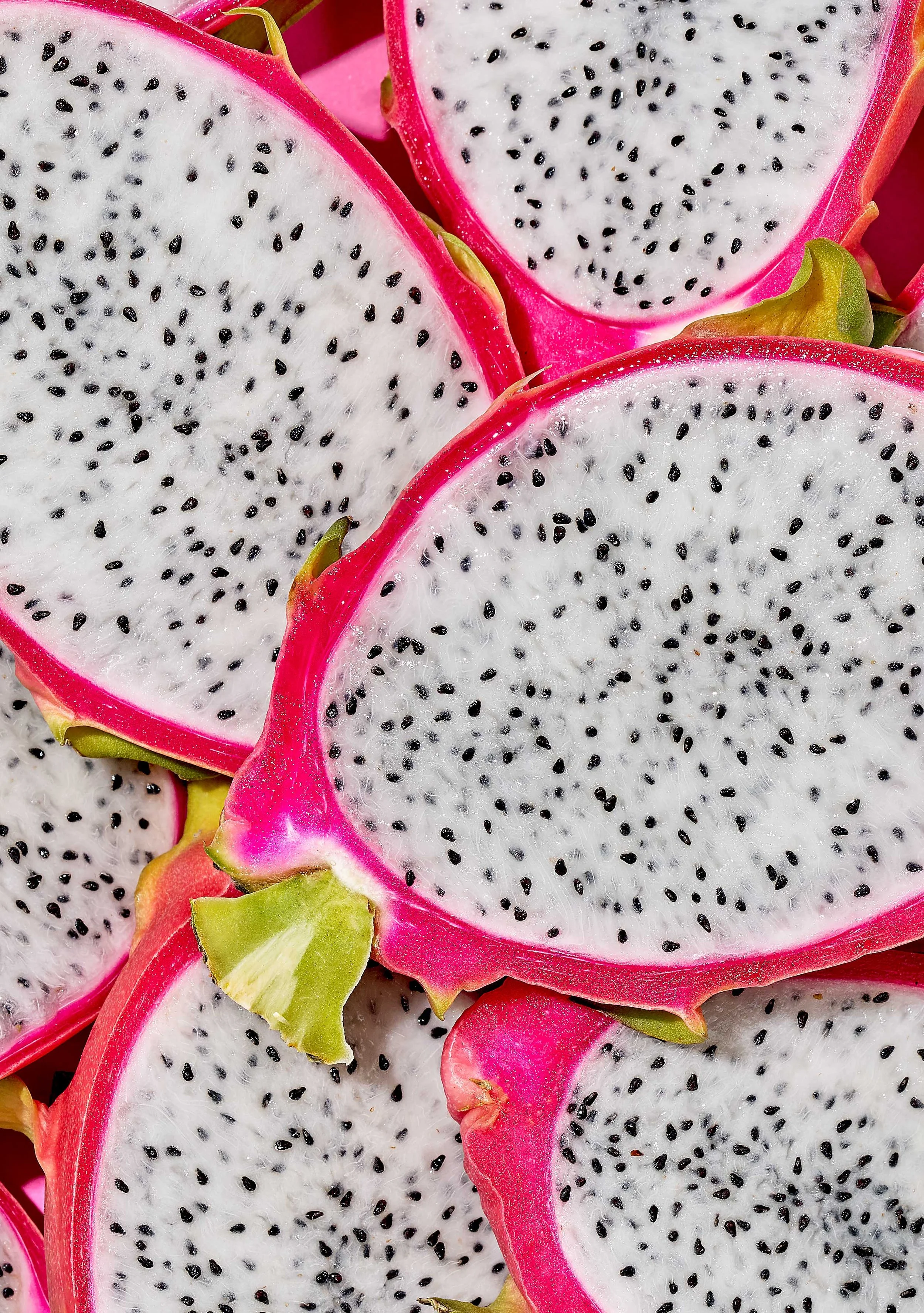 Overhead macro shot of sliced dragon fruit halves showing white flesh studded with black seeds and vivid magenta rind, styled for Suzanne Clements' Publix summer produce campaign.
