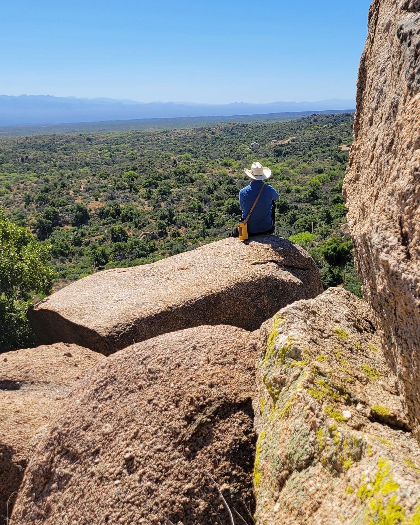 Sitting atop 1.4 billion year old Oracle Granite at the summit of the Granite Overlook Trail. Looking southeast across Oracle State Park, the San Pedro Valley and the distant Galiuro Mountains.&rdquo;. Photo by Tom Buckley