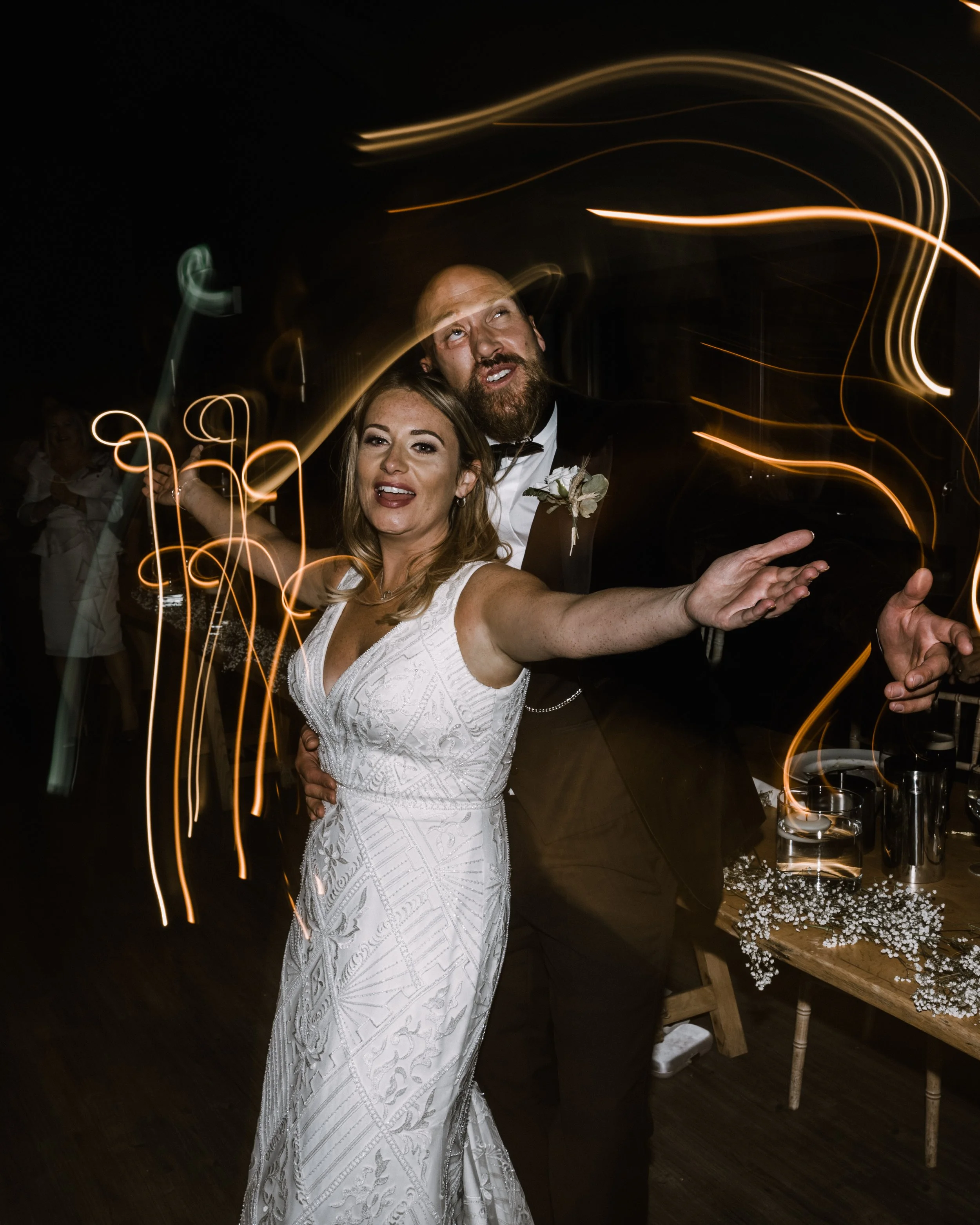 Couple dancing at a wedding with light trails in the background.