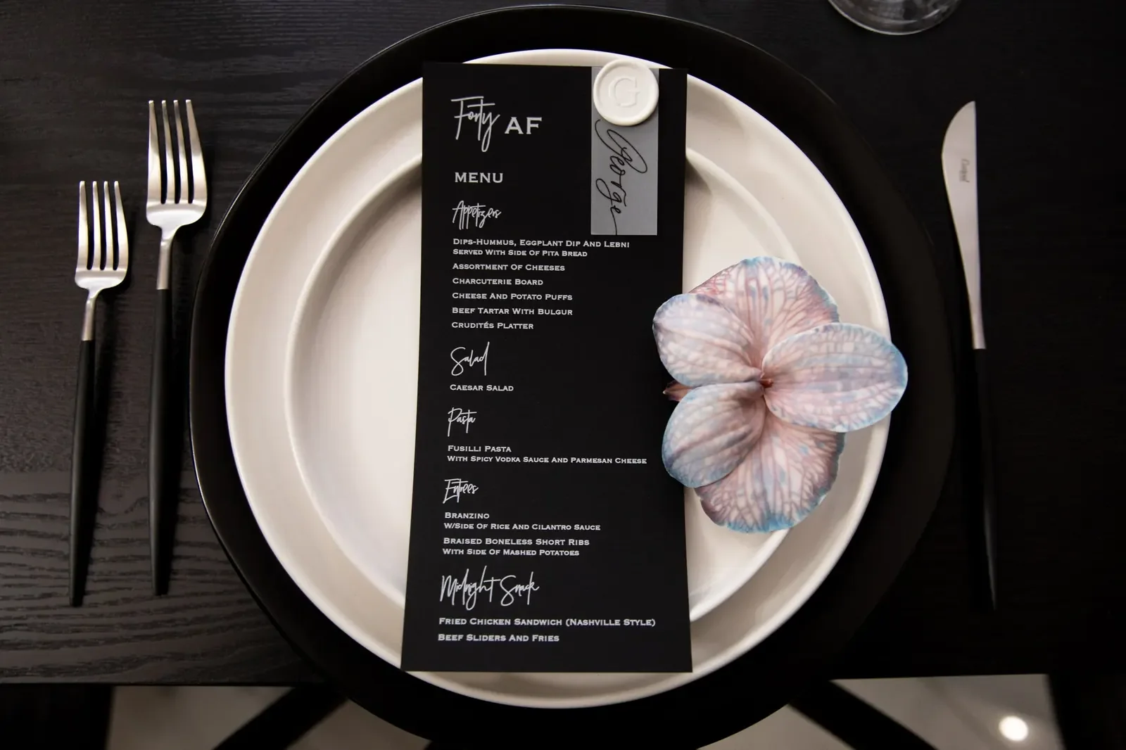 Black and white place setting with a custom menu card and fresh orchid, designed by a party planner