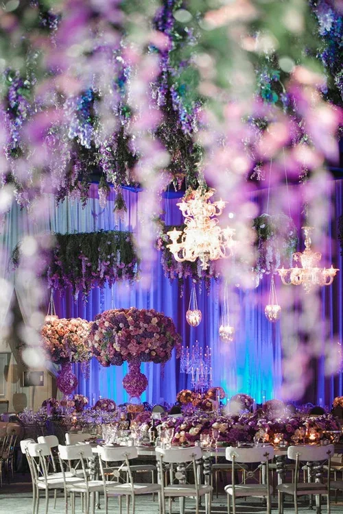 Purple wedding theme dance floor beneath a wisteria ceiling installation