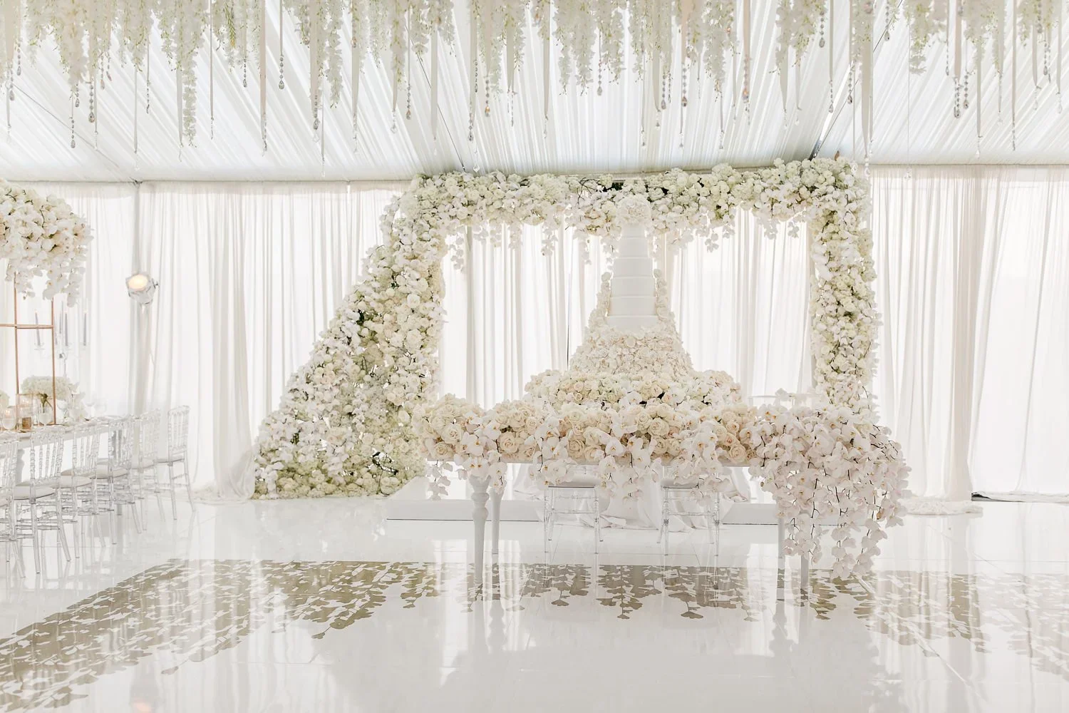 Tiered wedding cake with white floral arch backdrop