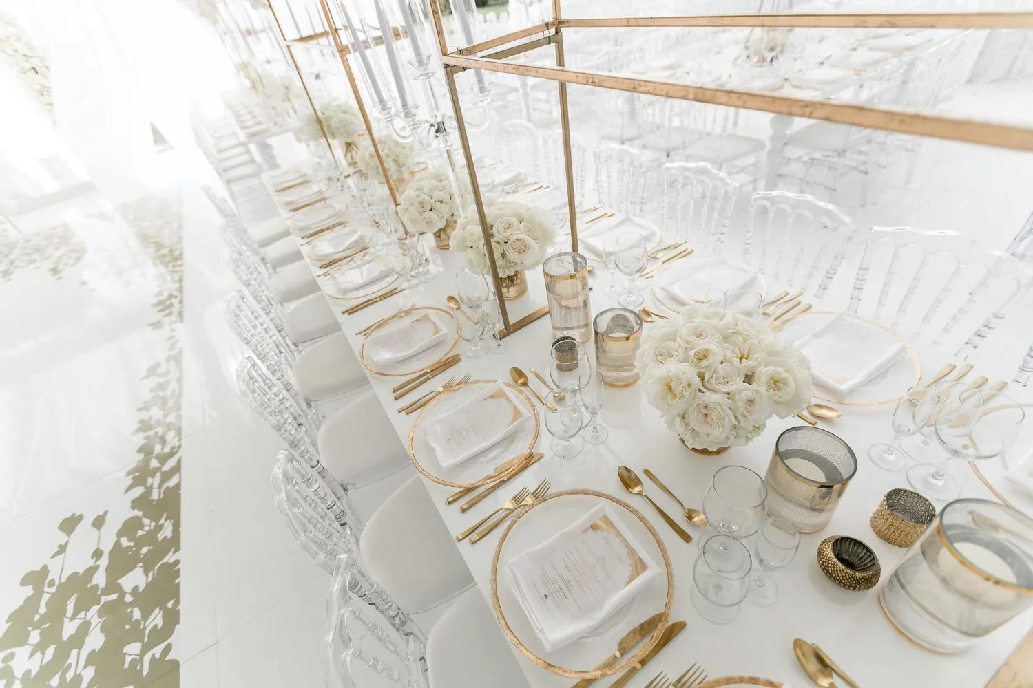 Gold chargers and flatware at a white wedding reception table setting
