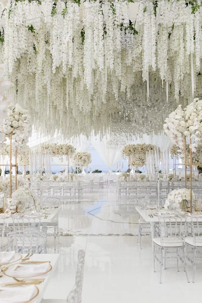 Draped wisteria ceiling installation over a tented wedding reception aisle