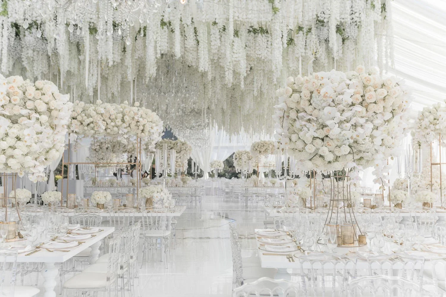 Tented wedding reception with hanging floral ceiling and dining aisle