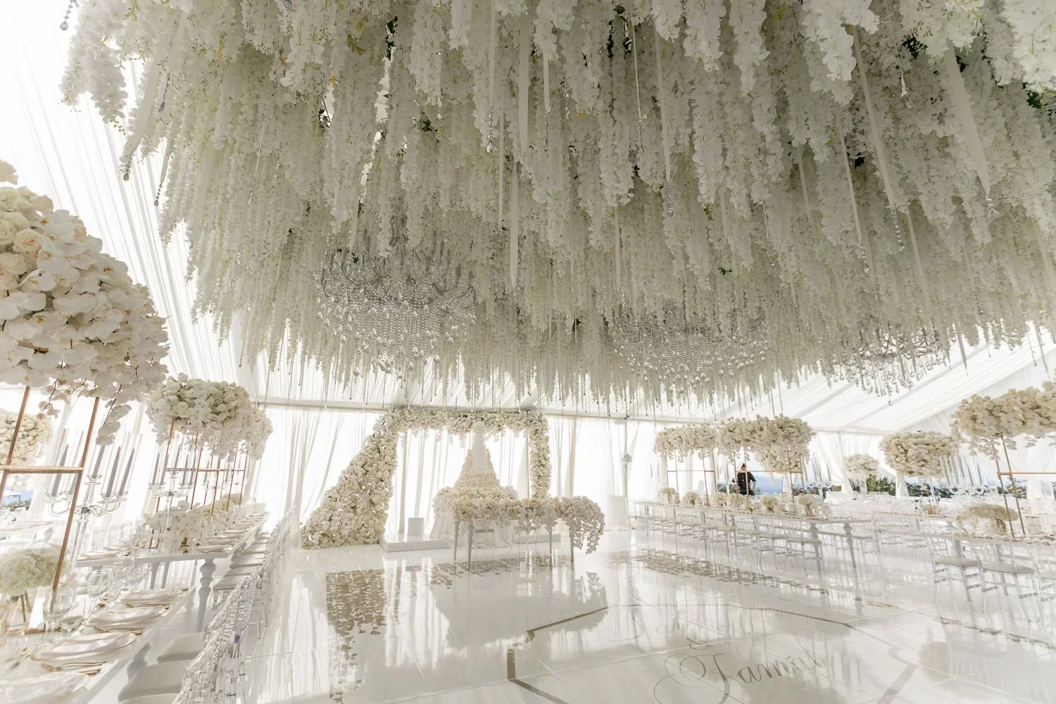 View toward the wedding cake through a draped wisteria ceiling installation
