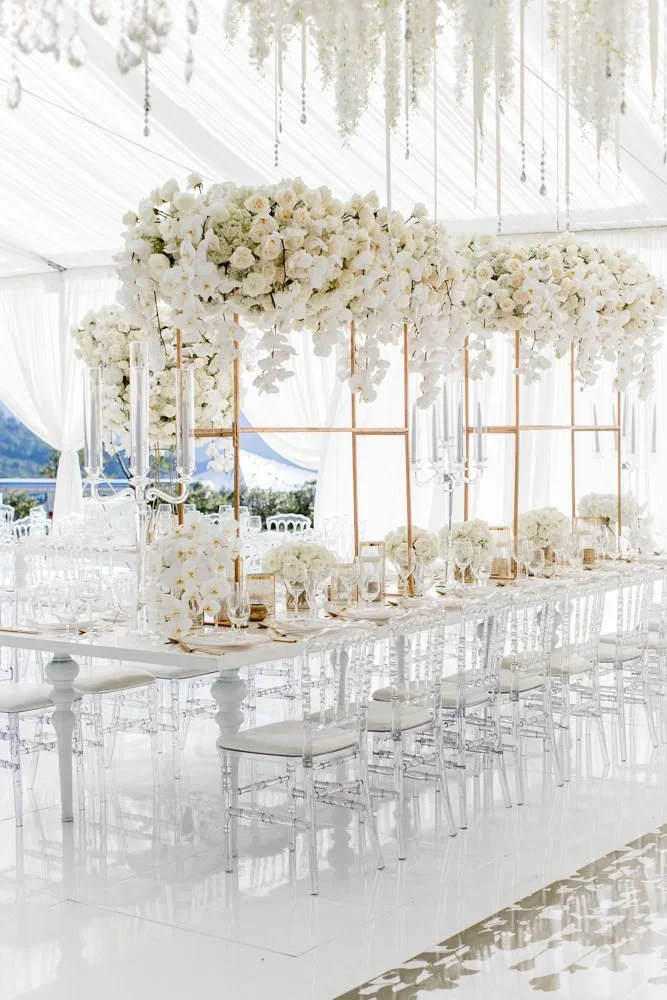 Long reception table with gold-framed floral installations and crystal candelabras