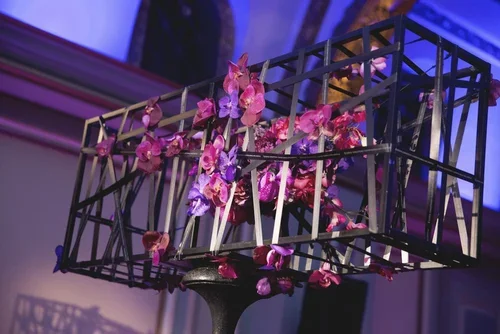 Close-up of purple wedding flowers in a modern orchid cage centerpiece
