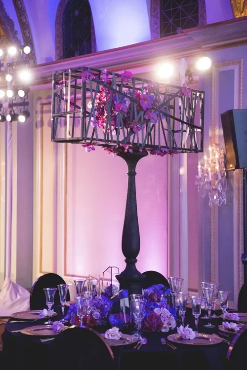 Purple wedding theme centerpiece with orchids in an iron cage stand
