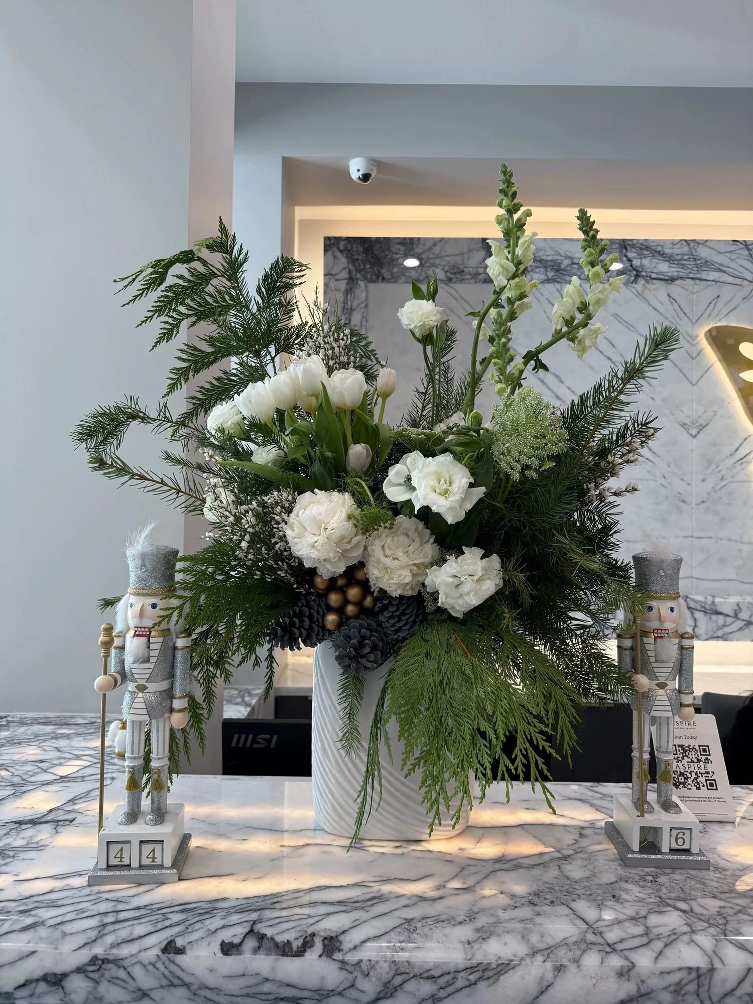 Holiday flower arrangement with white tulips, peonies and evergreens on a corporate reception desk, by Eddie Zaratsian in Los Angeles