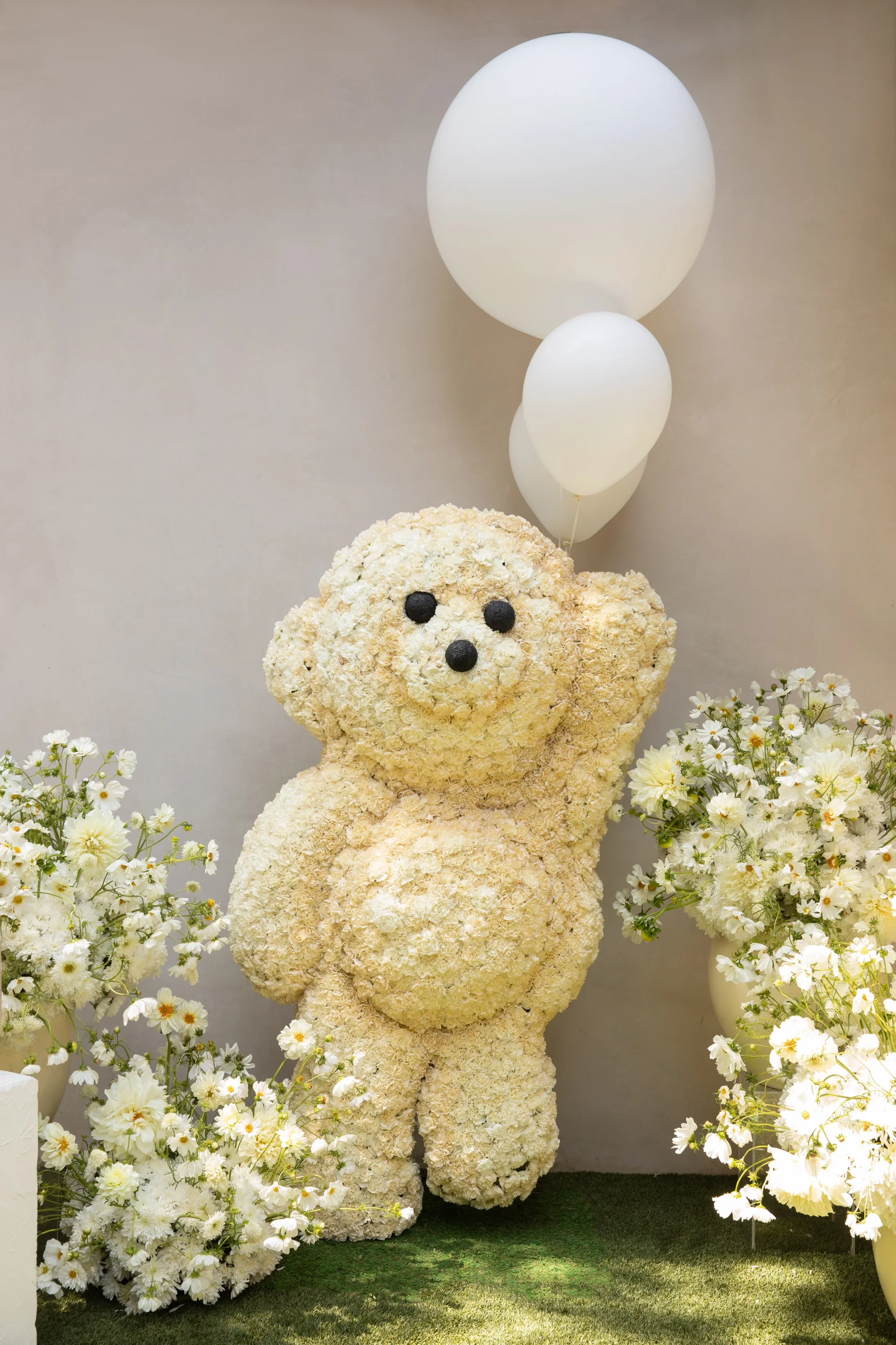 Custom floral teddy bear installation surrounded by spring flowers at a teddy bear baby shower