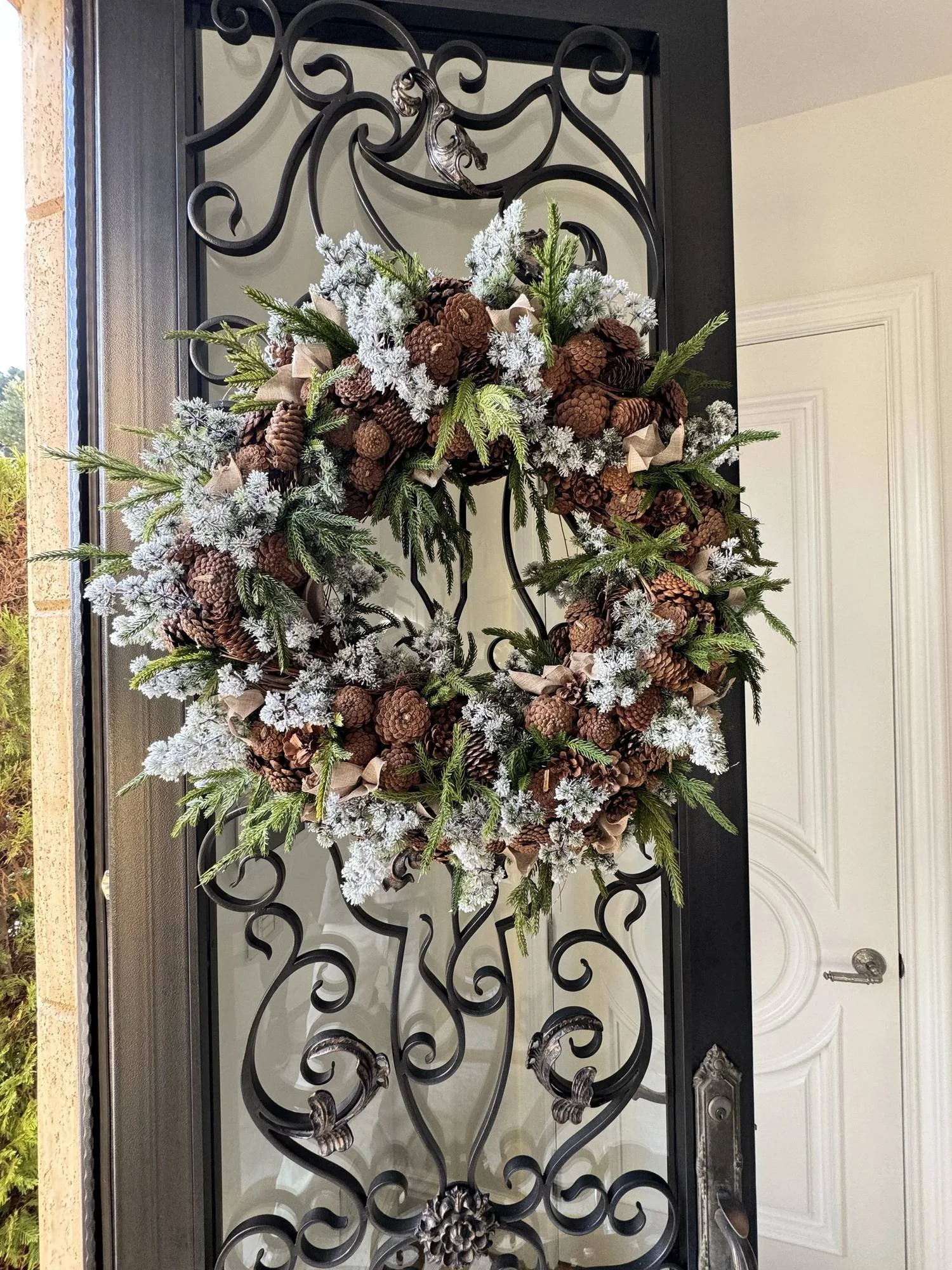 Custom Christmas wreath with pinecones, flocked greenery and linen ribbon on a front door, by Eddie Zaratsian in Los Angeles
