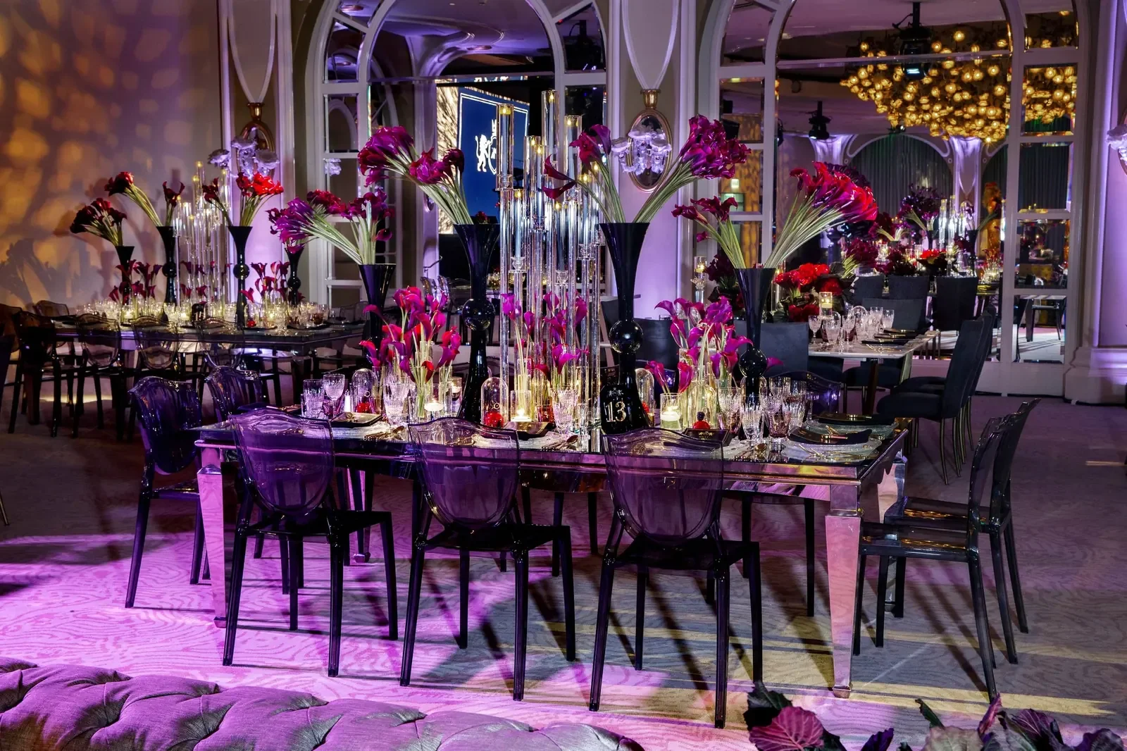 Purple ghost chairs and tall red calla lily centerpieces styled by a party planner for an elegant birthday dinner