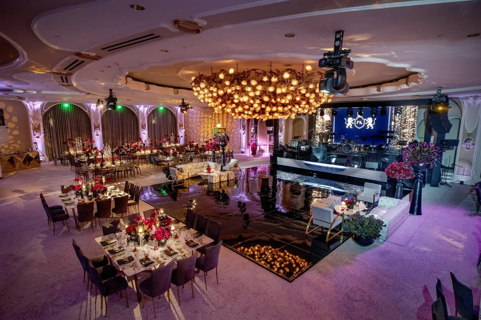 Gold flower chandelier over a mirrored dance floor at a birthday event produced by a party planner with a live stage setup