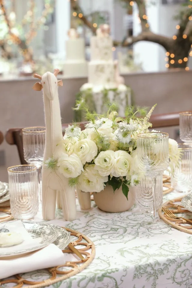 Teddy bear shower cake in background wiith string lights and cascasing greenery