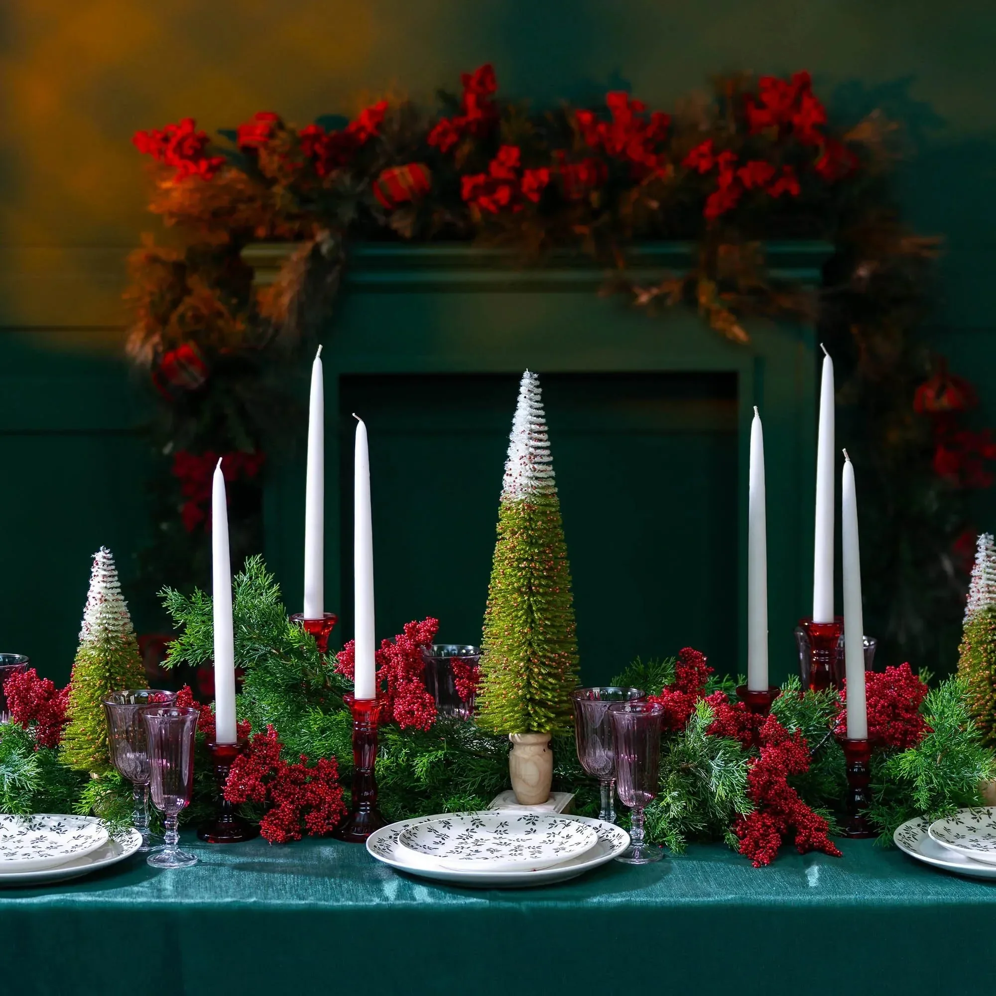 Red and green Christmas tablescape with bottle-brush trees, taper candles and a berry mantel garland, by Eddie Zaratsian in Los Angeles