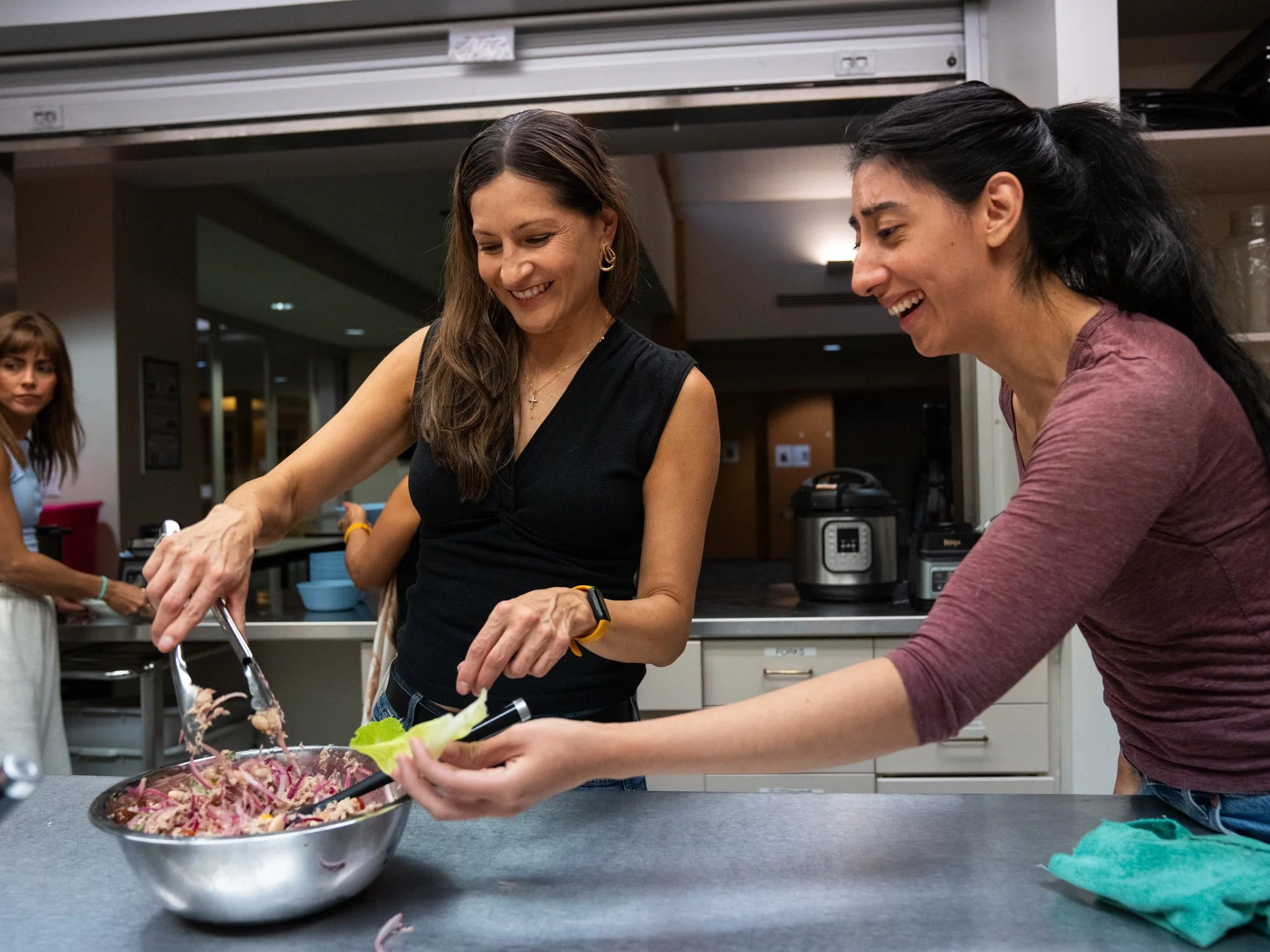 Two women in a community kitchen learning to cook