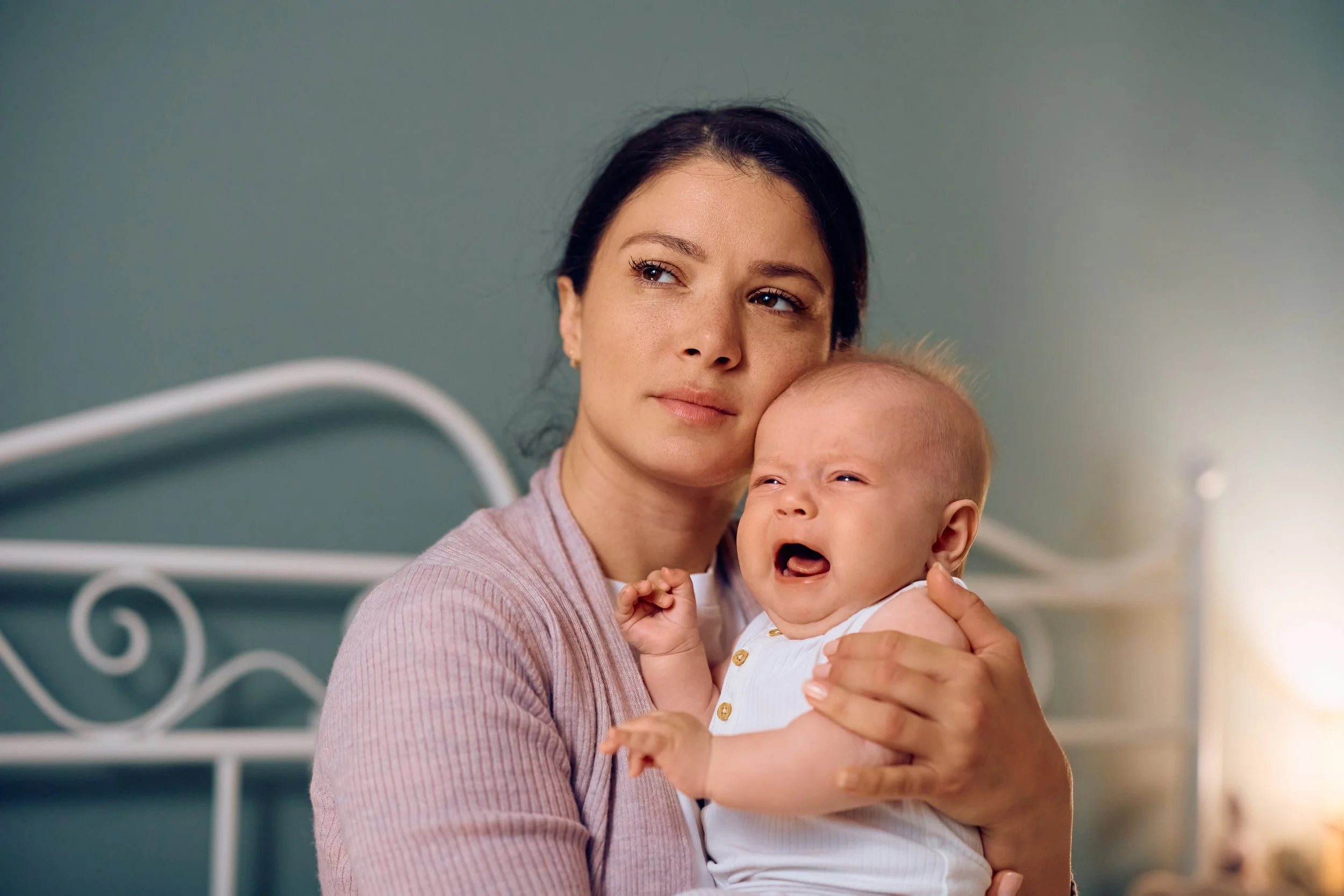 young-mother-holding-her-crying-baby-at-home-2024-12-13-18-34-21-utc.jpg