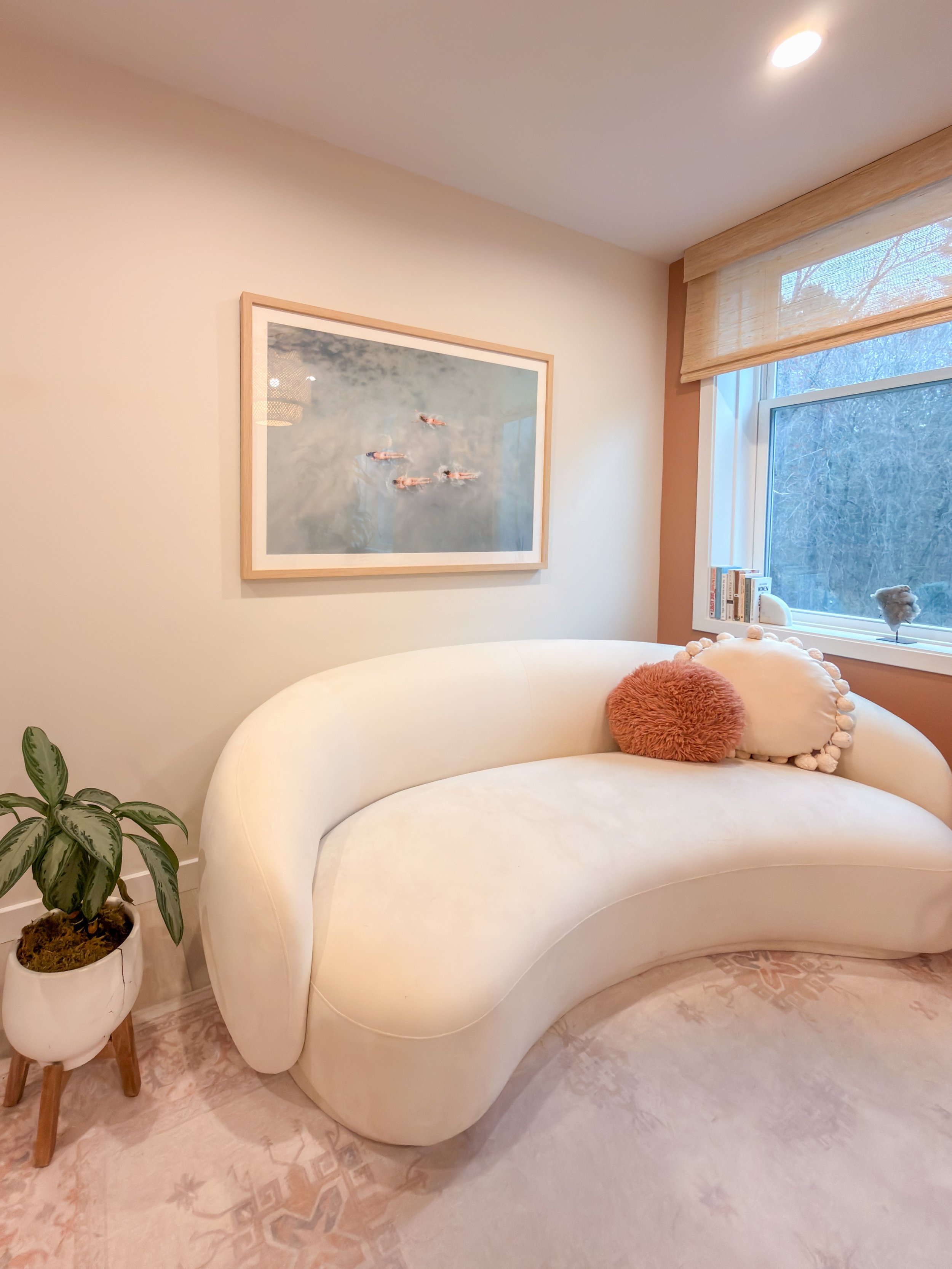 Calm lounge at Revival Wellness Studio in Medfield, MA with a curved cream sofa, artwork, and natural light