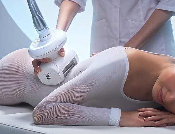 Endermologie body treatment using a motorized roller head over a treatment bodysuit