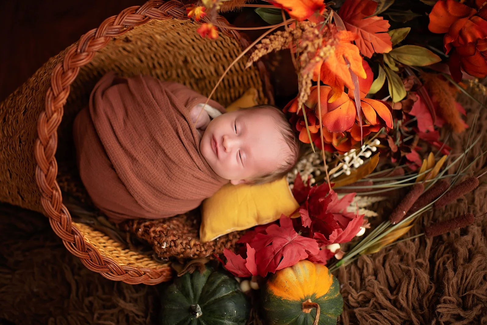 newborn baby asleep in  a cornucopia with fall florals