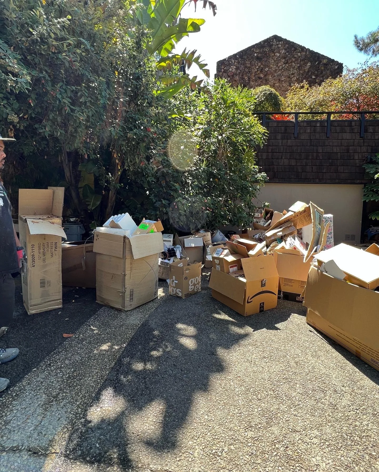 Cardboard boxes and household junk piled in a driveway ready for removal