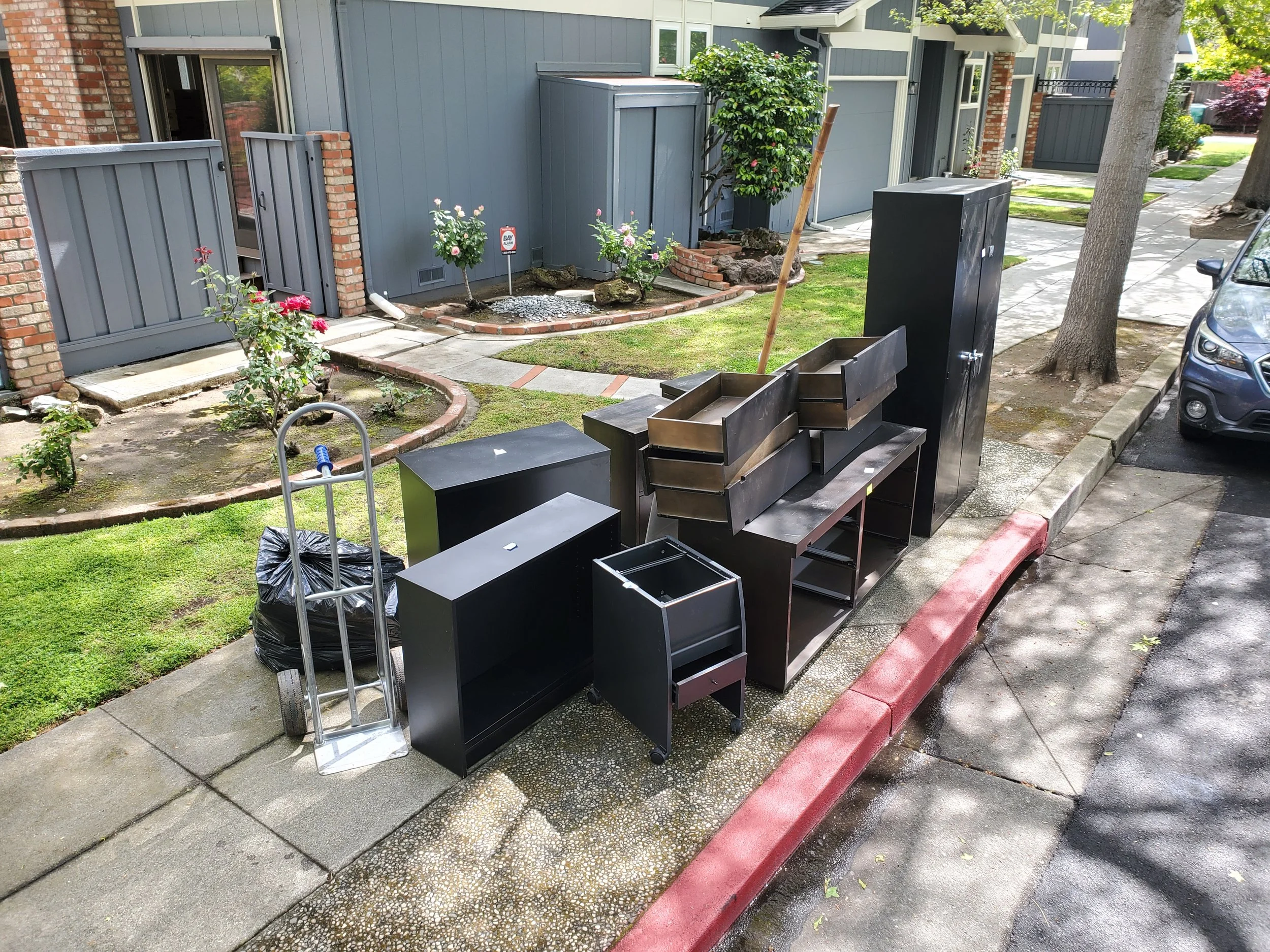 Office furniture and cabinets staged for removal outside a Bay Area building