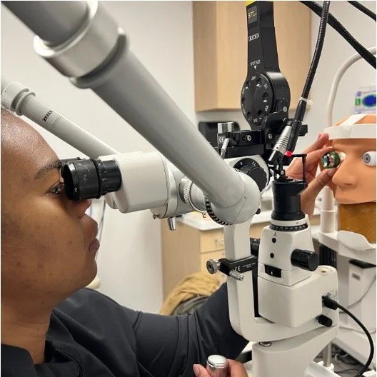 A person using a binocular microscope in a medical or laboratory setting.