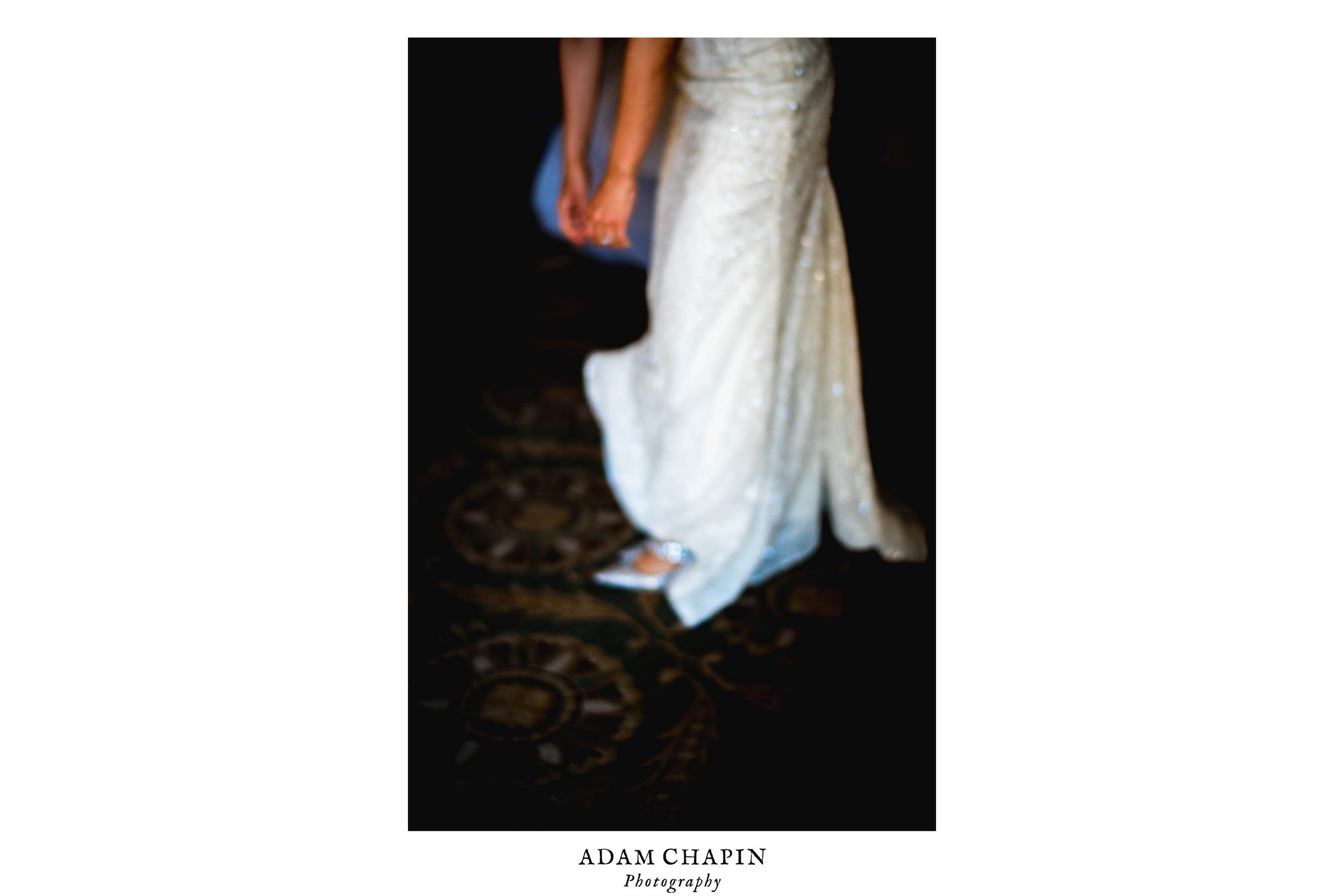 blurred image of bride in her white dress fixing her shoes