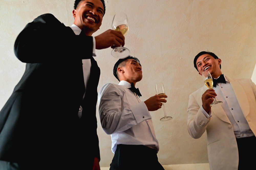 groom and groomsmen laughing and drinking champagne