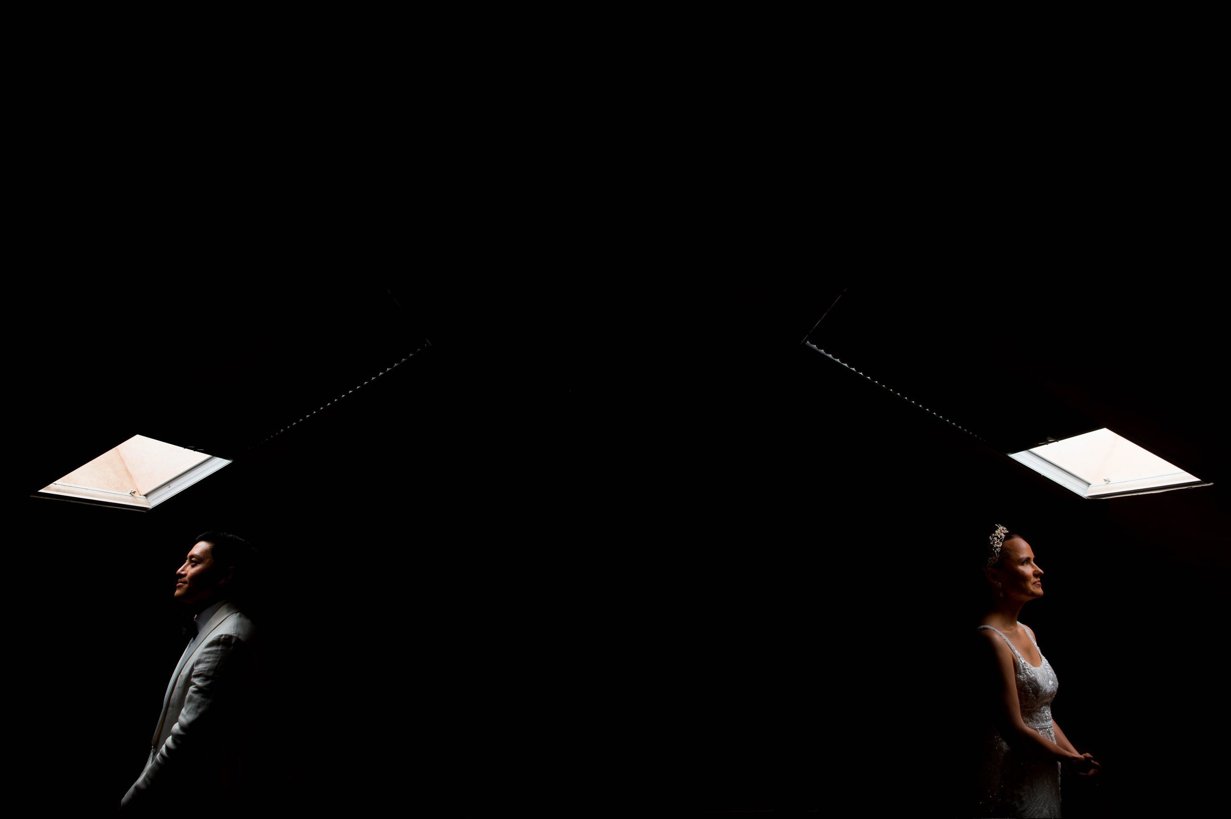 bride and groom staring up into skylights in a dark room