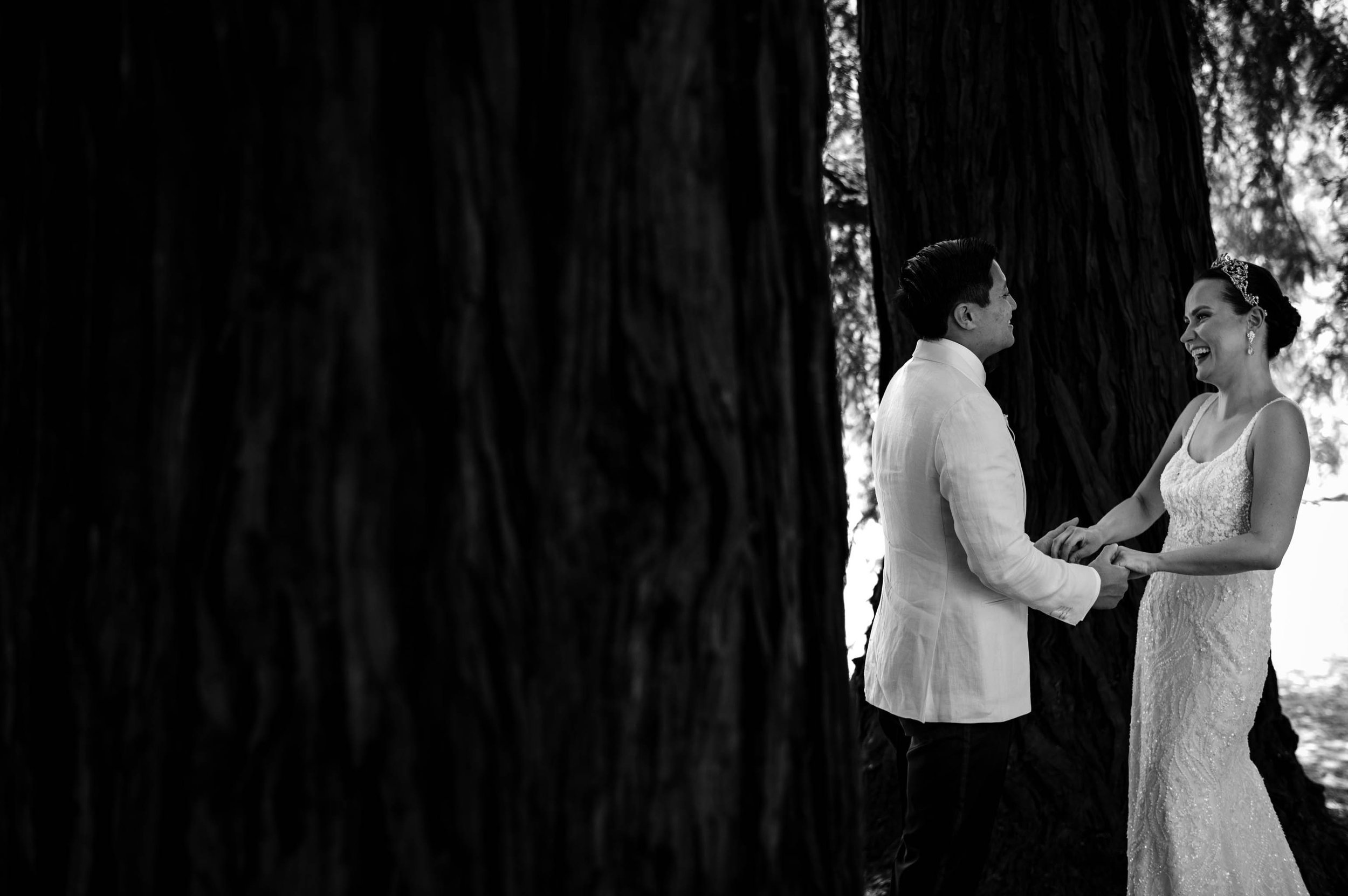bride and groom holding hands and laughing in the trees
