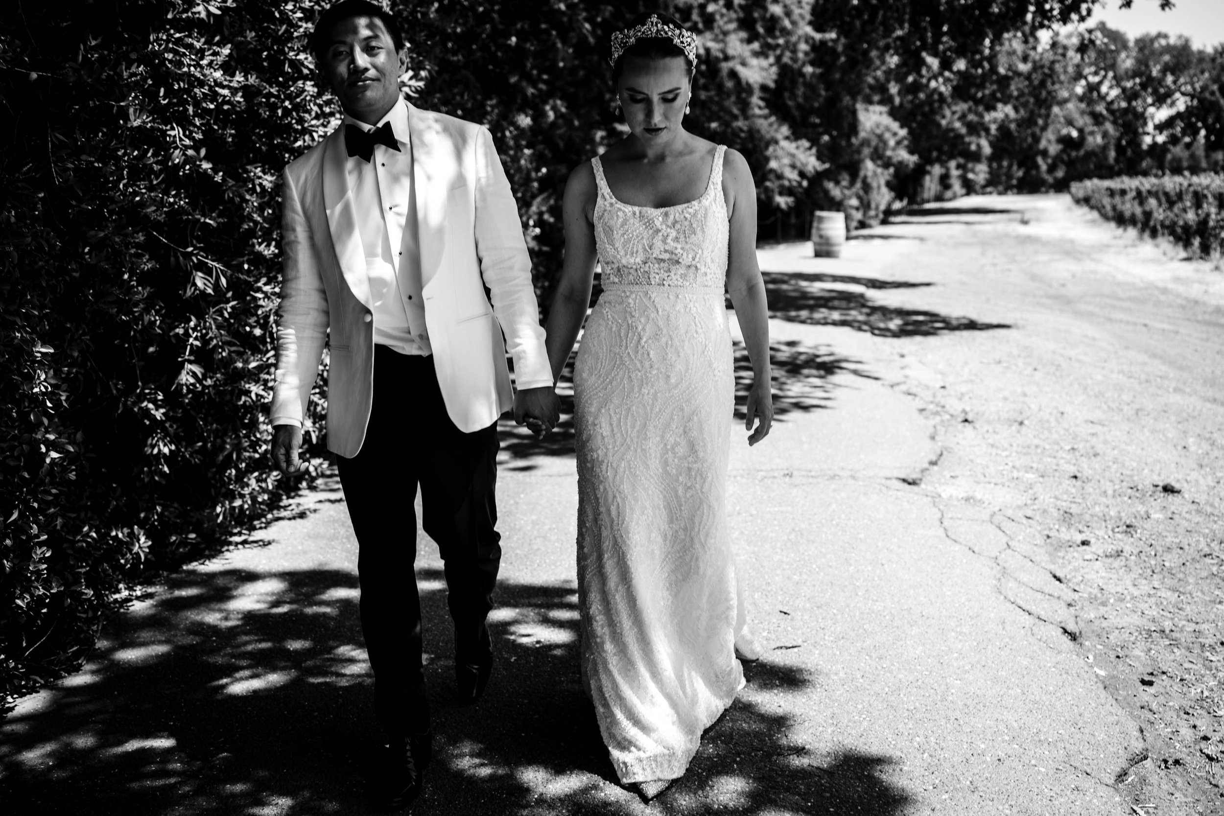 bride and groom holding hands and walking beside a vinyard in St Helena