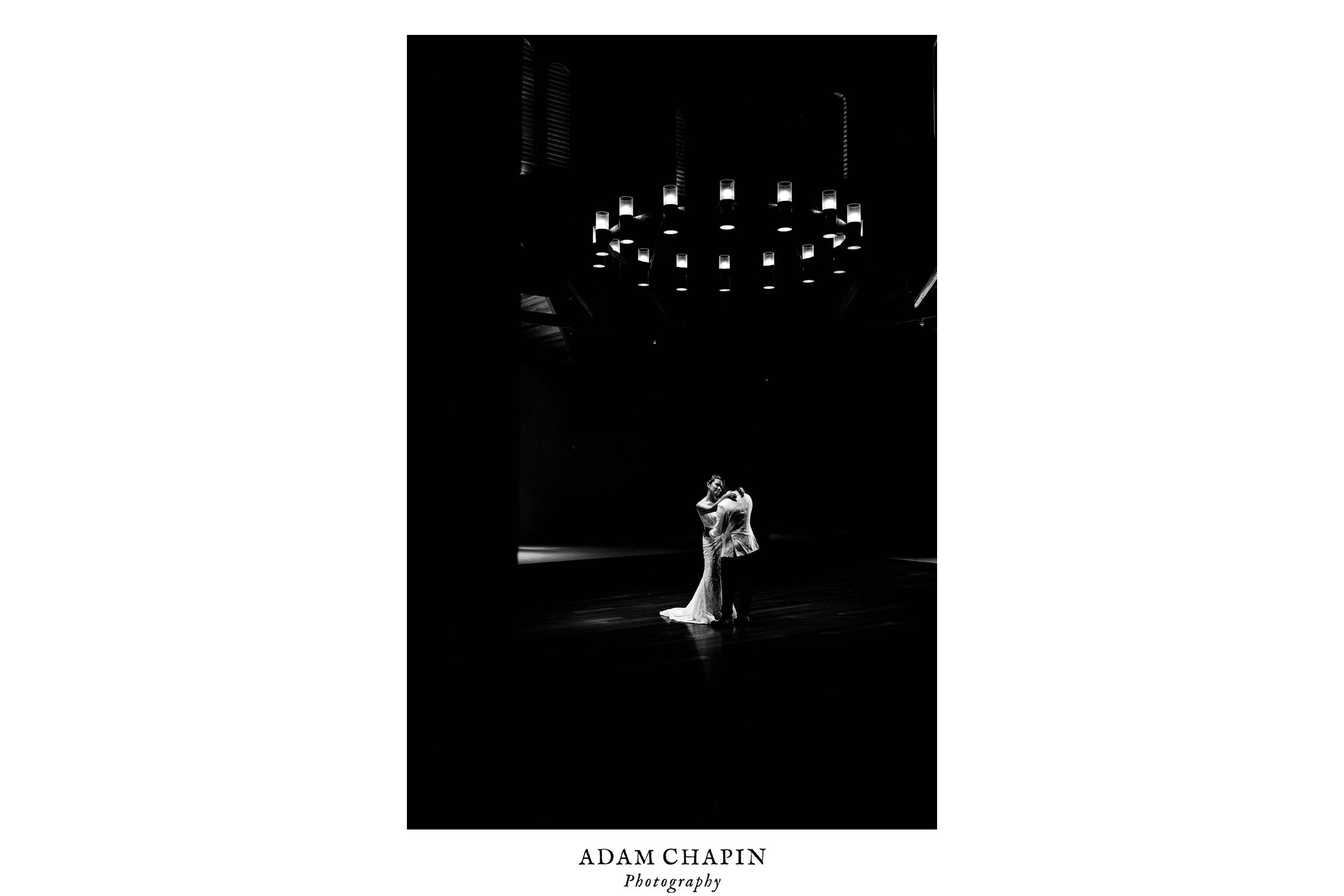 bride and groom practicing their dance beneath a large chandelier in the carriage house