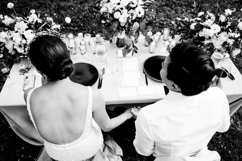 bride and groom holding hands while listening to a guest toast them