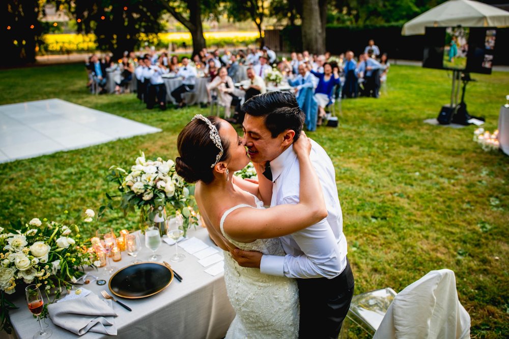the bride and groom share a big kiss in front of their guests after dinner