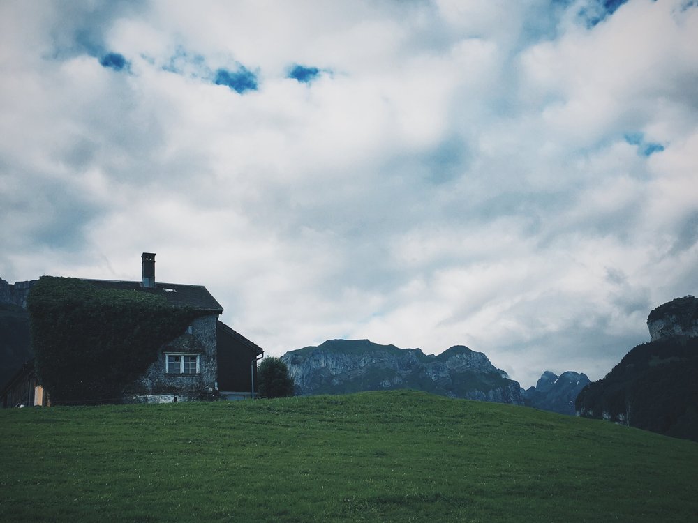 old farmhouse on a grassy hilltop in weissbad switzerland by adam chapin photography