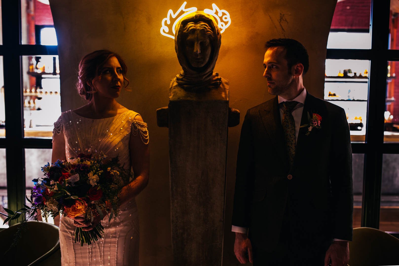 bride and groom pose in front of art piece in vidrio raleigh