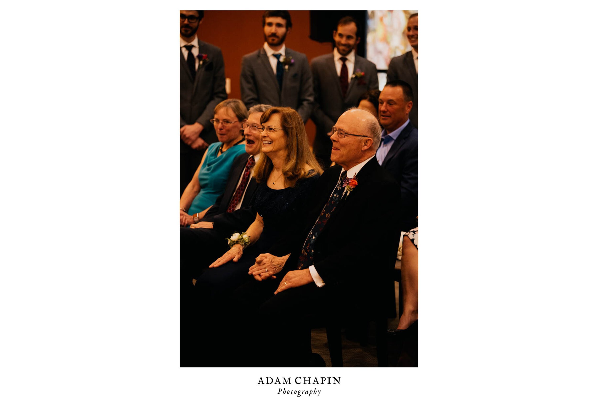 grooms parents and family laughing at a joke during the ceremony