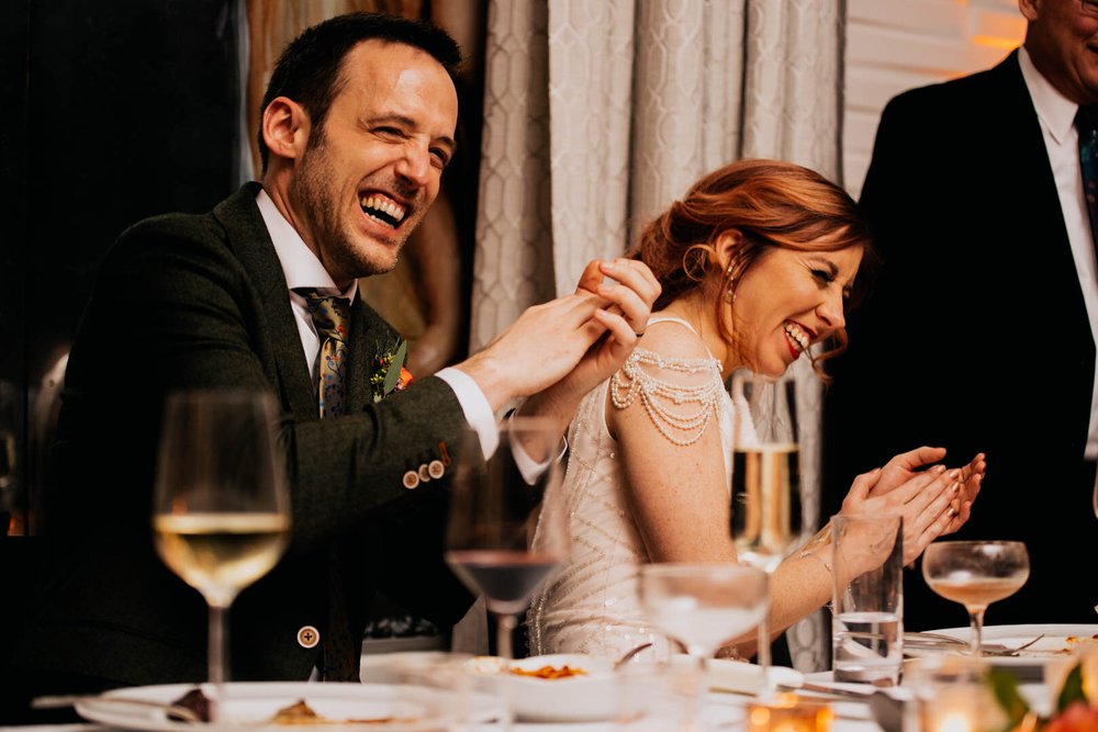 bride and groom laughing during speeches at dinner