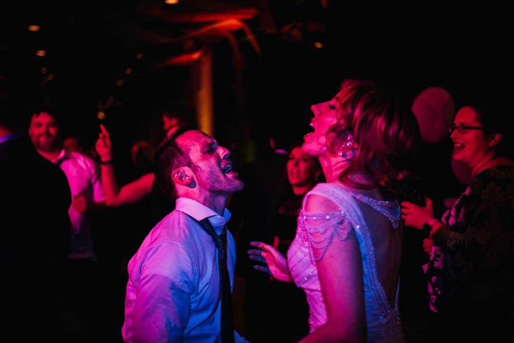 bride and groom singing and dancing with each other during their wedding reception