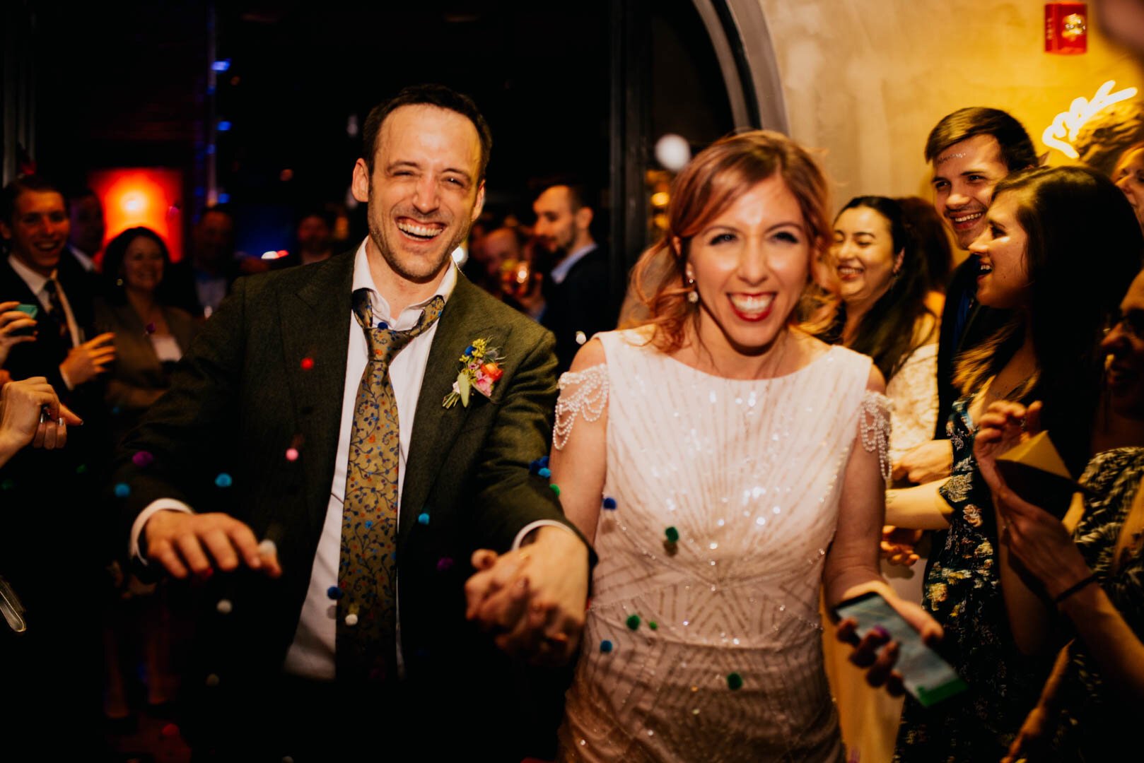 bride and groom exit their wedding while poof balls get thrown at them