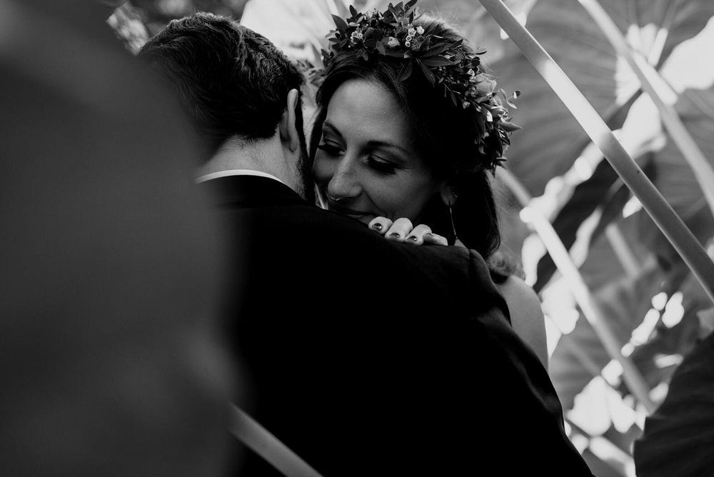 bride hugging groom under large plant leaves